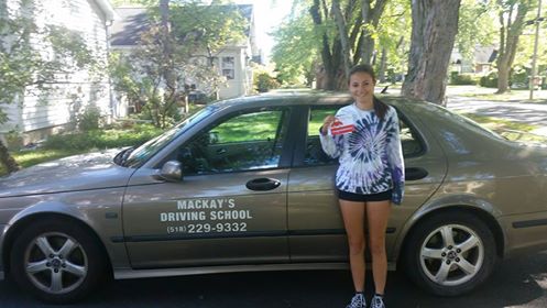 A young driver posing with the Mackay's Driving School car